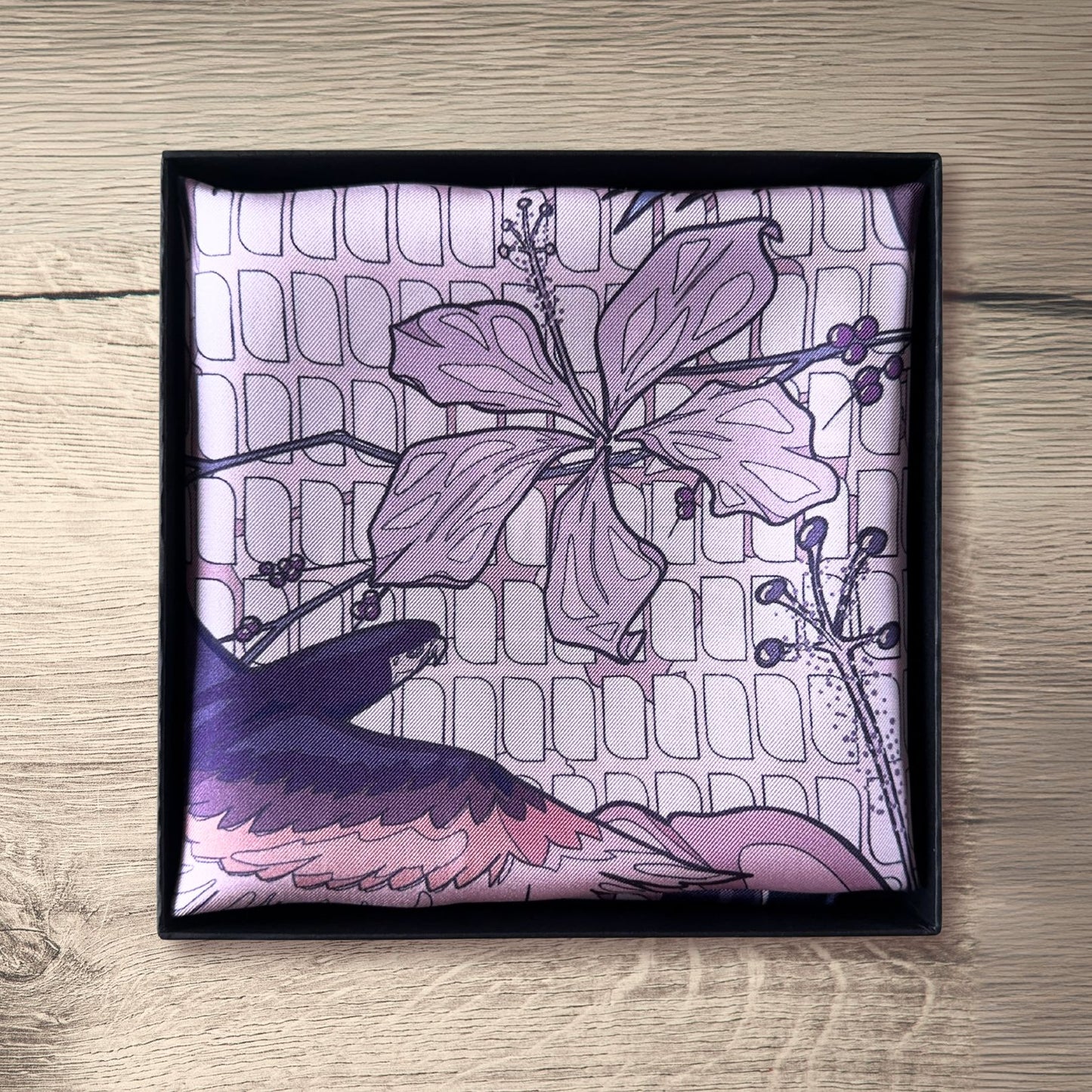 Pink purple, and navy blue pocket square folded in packaging on rustic wooden table