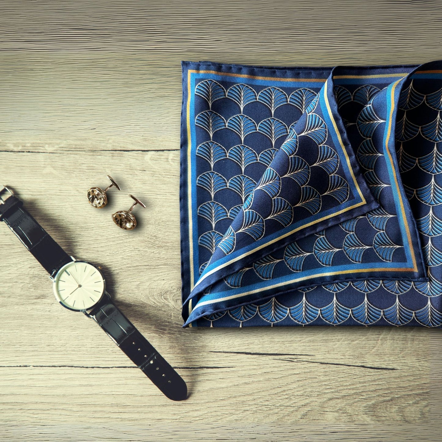 BLUEMATERIALS Midnight blue & gold silk pocket square on a rustic table next to a smart watch and bronze cufflincs - hand-drawn Art Deco Fans design
