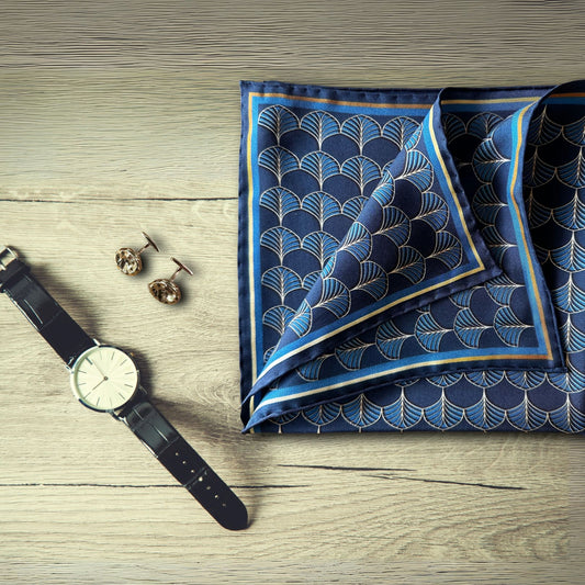 BLUEMATERIALS Midnight blue & gold silk pocket square on a rustic table next to a smart watch and bronze cufflincs - hand-drawn Art Deco Fans design