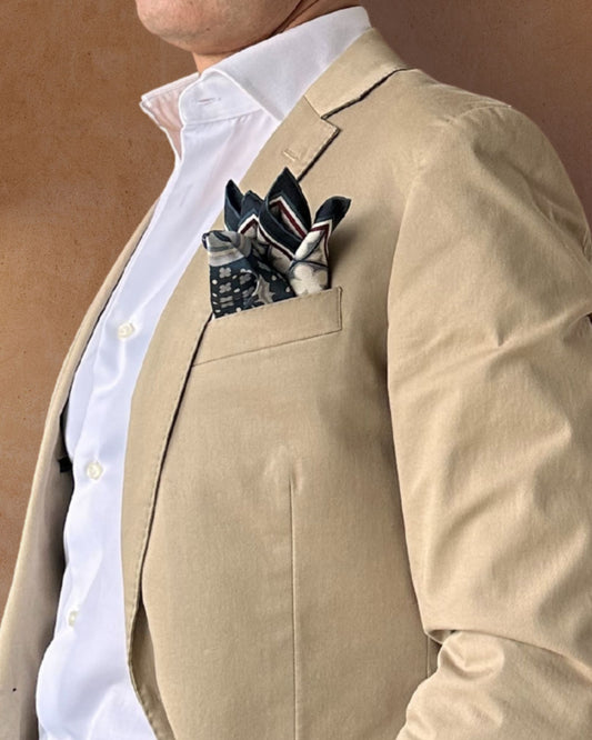Blue cream and burgundy pocket square on the lapel pocket of a cream suit jacket 